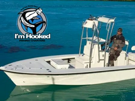 A person is sitting on a white boat in turquoise water with 