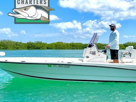 A person stands on a white boat on clear turquoise water with 