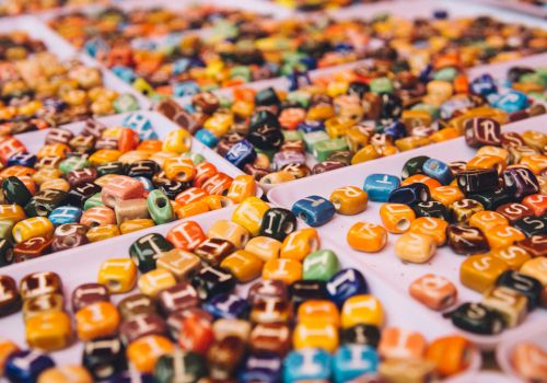 The image shows trays filled with colorful, lettered beads, possibly for crafting or jewelry-making purposes, arranged in a random order.